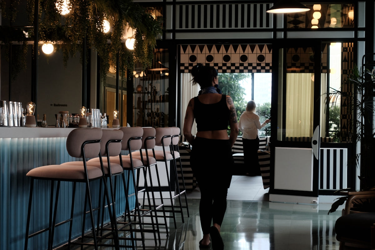 Woman walks into a stylish bar with stools.